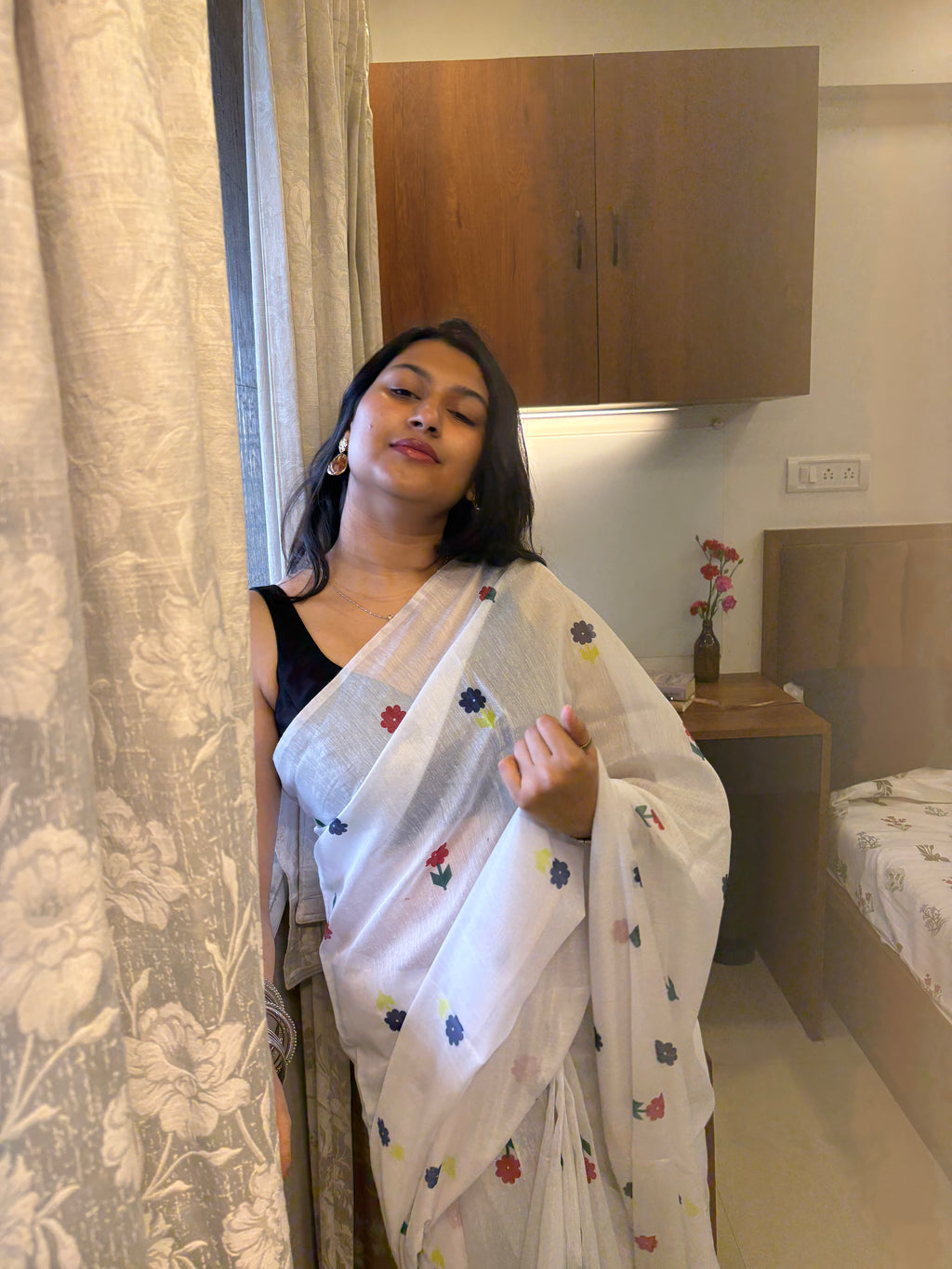 Woman wearing a white saree with colorful patterns in a room.
White cotton saree, white sari, white saree, cotton sari, sari for women